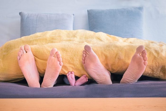 Parents and baby feet in bed